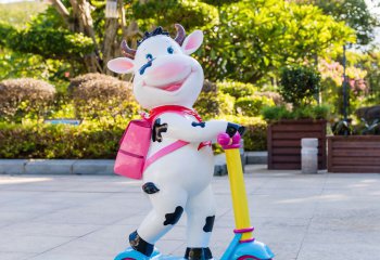 牛雕塑-幼兒園一只騎車背包的玻璃鋼卡通牛雕塑